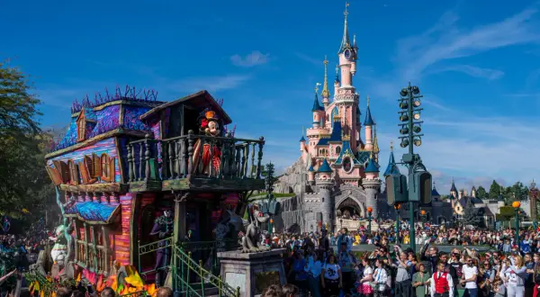 Desfile de **Disneyland Paris Halloween** con Mickey Mouse en un carro espeluznante frente al castillo.