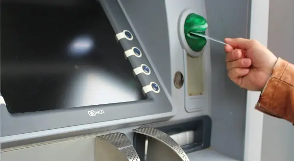 Mano insertando una tarjeta N26 extranjero en un cajero automático.