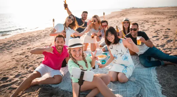 Un grupo de amigos celebra en la playa, un lugar perfecto para disfrutar del sol y la compañía.