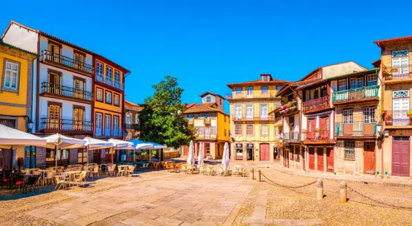 Plaza con edificios coloridos y terrazas. Un lugar perfecto donde viajar en marzo Europa para disfrutar del sol y la arquitectura.