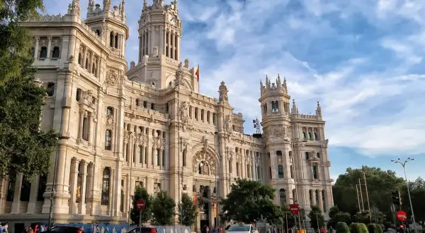 Edificio de Correos y Telégrafos, un lugar clave que ver en Madrid en un día. Fachada monumental, torre con reloj y cielo azul.