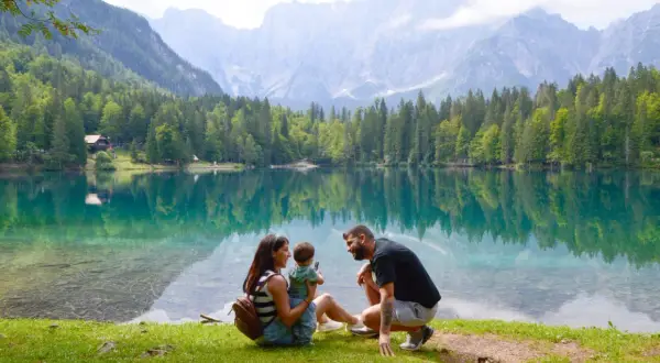 Familia disfrutando del lago turquesa y montañas, un lugar idílico que ver en Eslovenia.
