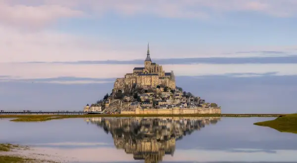 Mont Saint-Michel como llegar: la abadía reflejada en el agua, un sueño al amanecer.