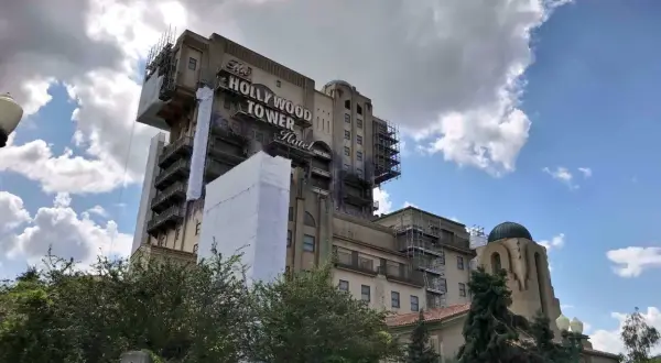 La imponente Hollywood Tower Hotel de Disneyland Paris, con andamios y cubiertas, se alza bajo un cielo nublado.