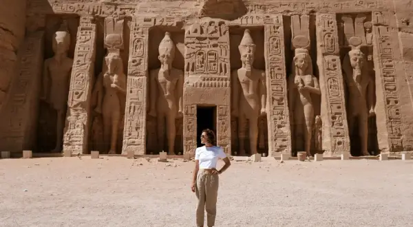 Mujer posa frente a colosales estatuas en Abu Simbel. ¡Excelentes consejos para viajar a Egipto!