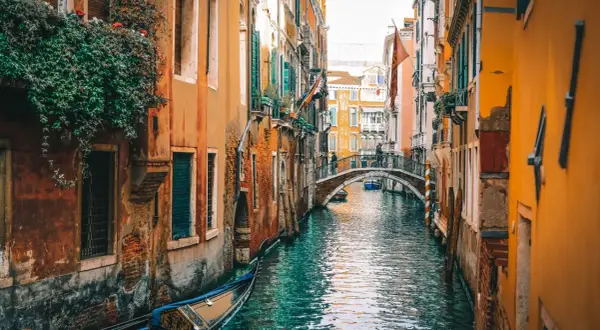 Un canal veneciano con góndola y un puente. El viaje de Milán a Venecia es un sueño hecho realidad.