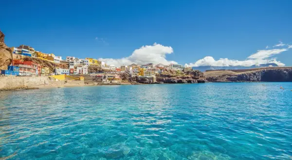 Pueblo costero de casas coloridas en una ladera rocosa, con aguas cristalinas. ¡Un destino ideal donde viajar en febrero barato!