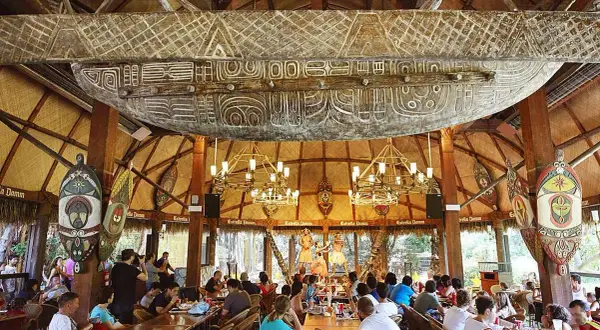 Comedor temático con decoración polinesia, similar a Bora Bora, en PortAventura. Gente disfrutando de un espectáculo.