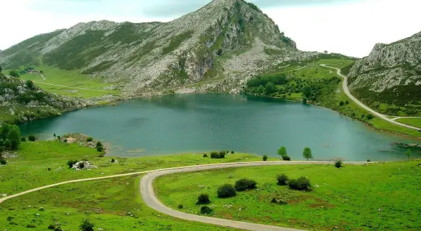 Lago en Cangas de Onís que ver: un paisaje montañoso verde con un lago sereno y carreteras serpenteantes.