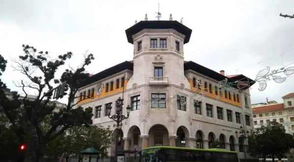 Autobús verde de ALSA en la calle, frente a un edificio histórico. Un buen lugar para aparcar en Santander y disfrutar de la arquitectura.