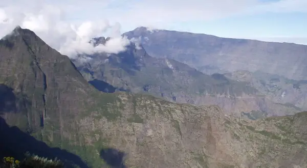 Impresionantes montañas en la isla Reunión, con nubes que envuelven picos escarpados, sugiriendo los peligros de su terreno.