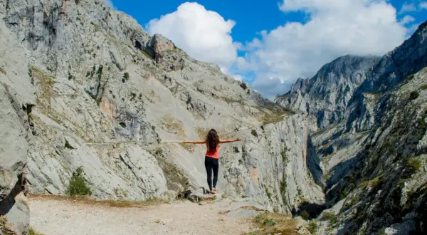 Mujer con brazos extendidos en un desfiladero rocoso, disfrutando de la vista. ¡Una aventura de Cantabria en 4 días!