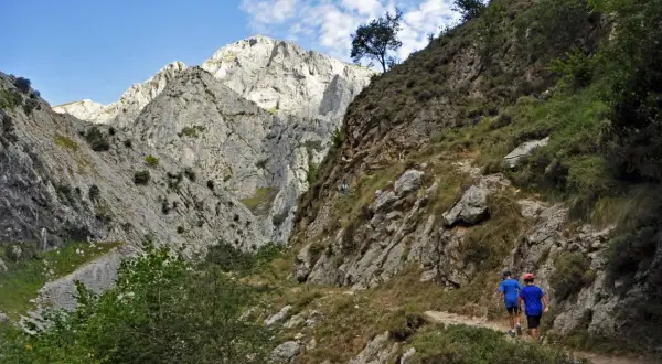 Dos niños caminan por un sendero rocoso en un desfiladero, una ruta para llegar a Bulnes.