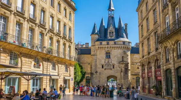 Plaza con la Giralda de Burdeos y edificios históricos. Gente paseando y disfrutando de terrazas. Merece la pena visitar Burdeos.
