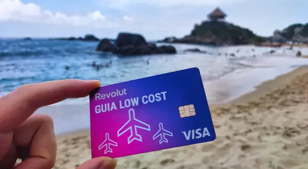 Tarjeta Revolut "Guía Low Cost" en una playa paradisíaca. Descubre cómo funciona Revolut en el extranjero sin comisiones ocultas.