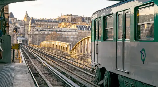 Un tren del metro de París cruza un puente al atardecer. El horario del metro de París es fácil de consultar para planificar tu viaje.