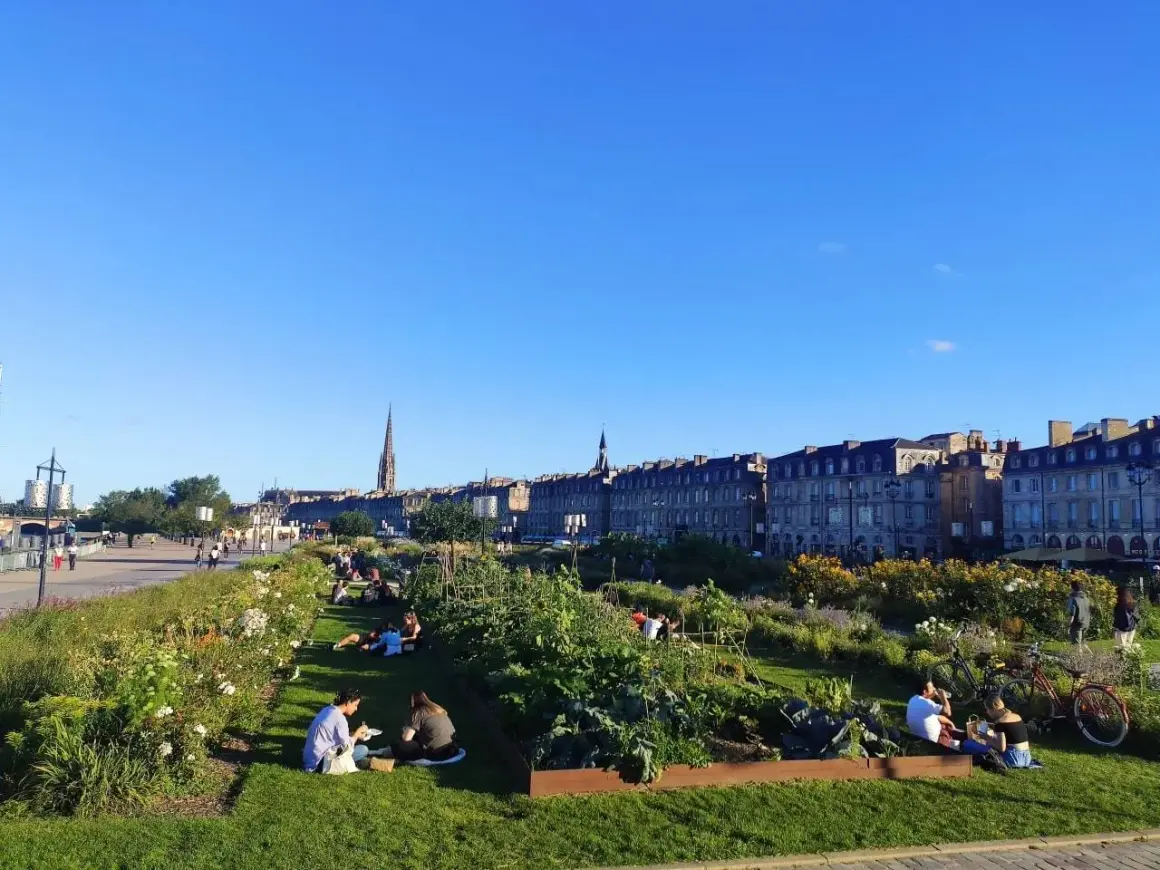 Gente relajándose en un jardín urbano con vistas a Burdeos. ¡Así se llega a la tranquilidad!