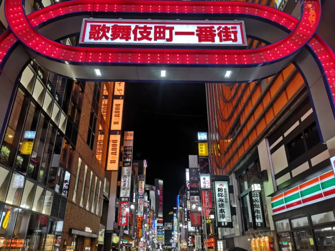 Entrada al barrio rojo de Tokio, con un letrero brillante y luces rojas.