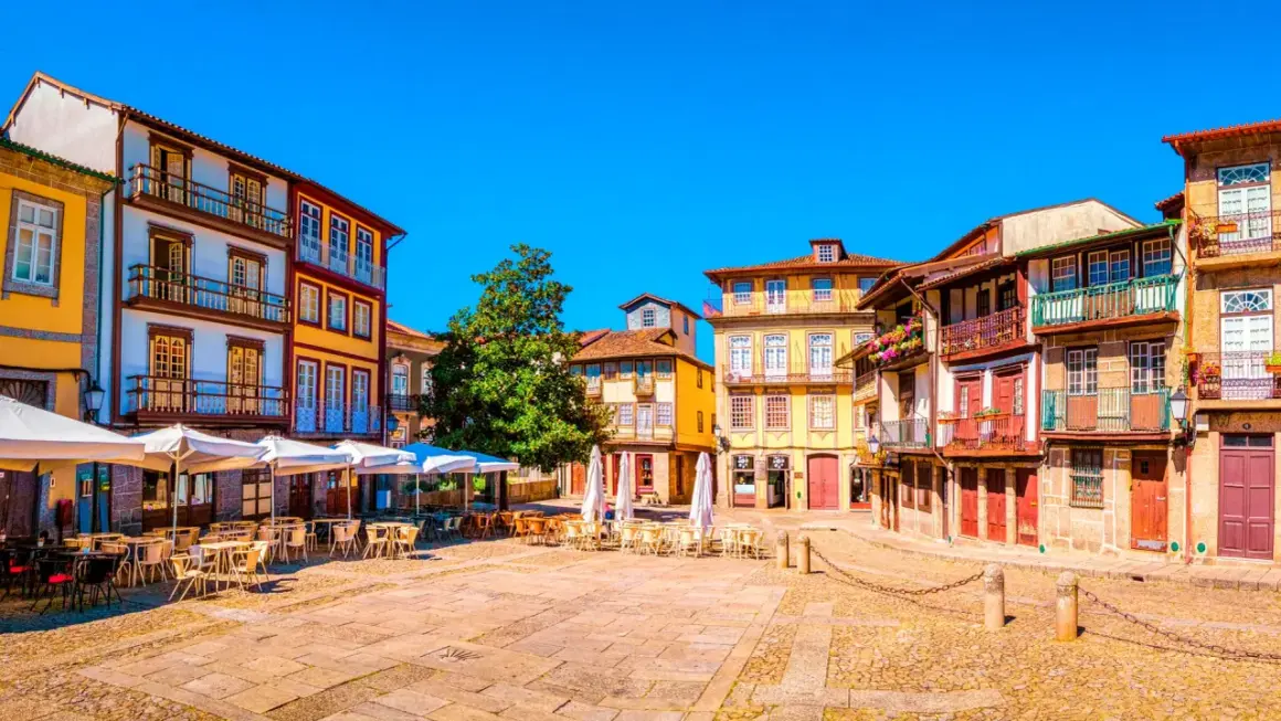 Plaza con edificios coloridos y terrazas. Un lugar perfecto donde viajar en marzo Europa para disfrutar del sol y la arquitectura.