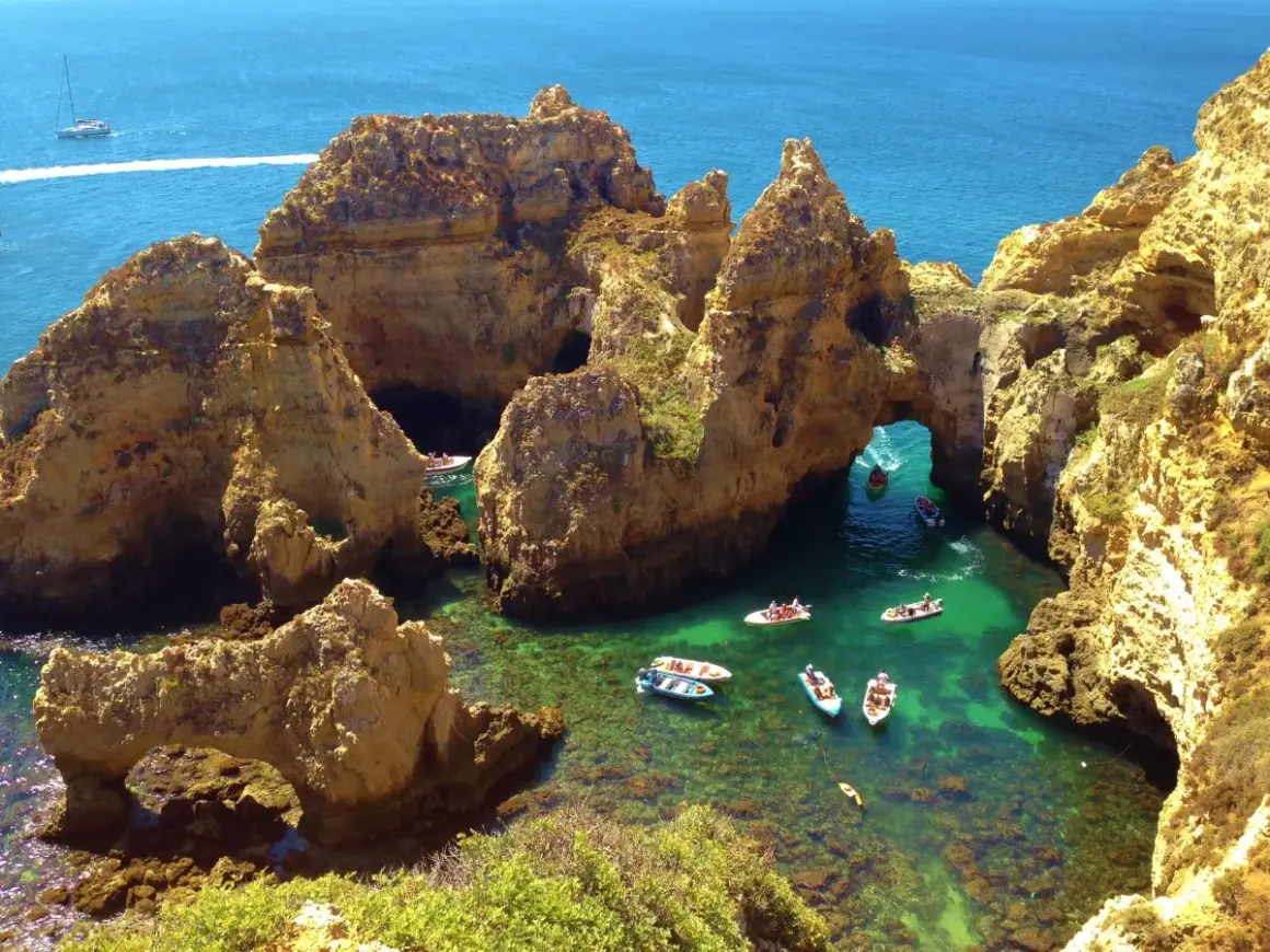 ¡Qué ganas de ir al Algarve en coche! Aquí, barcos exploran cuevas y arcos naturales en aguas cristalinas.