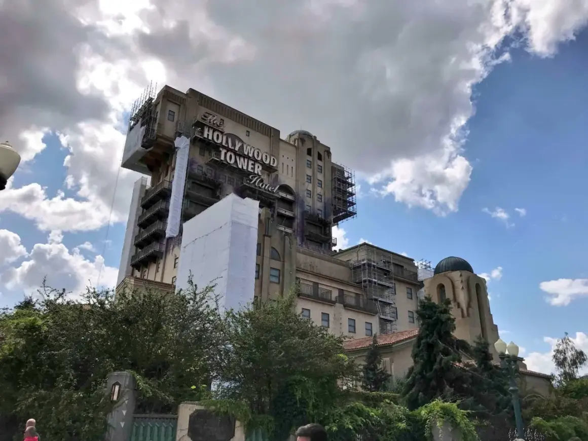 La imponente Hollywood Tower Hotel de Disneyland Paris, con andamios y cubiertas, se alza bajo un cielo nublado.