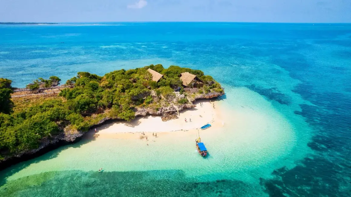 Isla tropical con cabañas y playa de arena blanca, aguas turquesas. La mejor época para viajar a Zanzíbar es ahora.