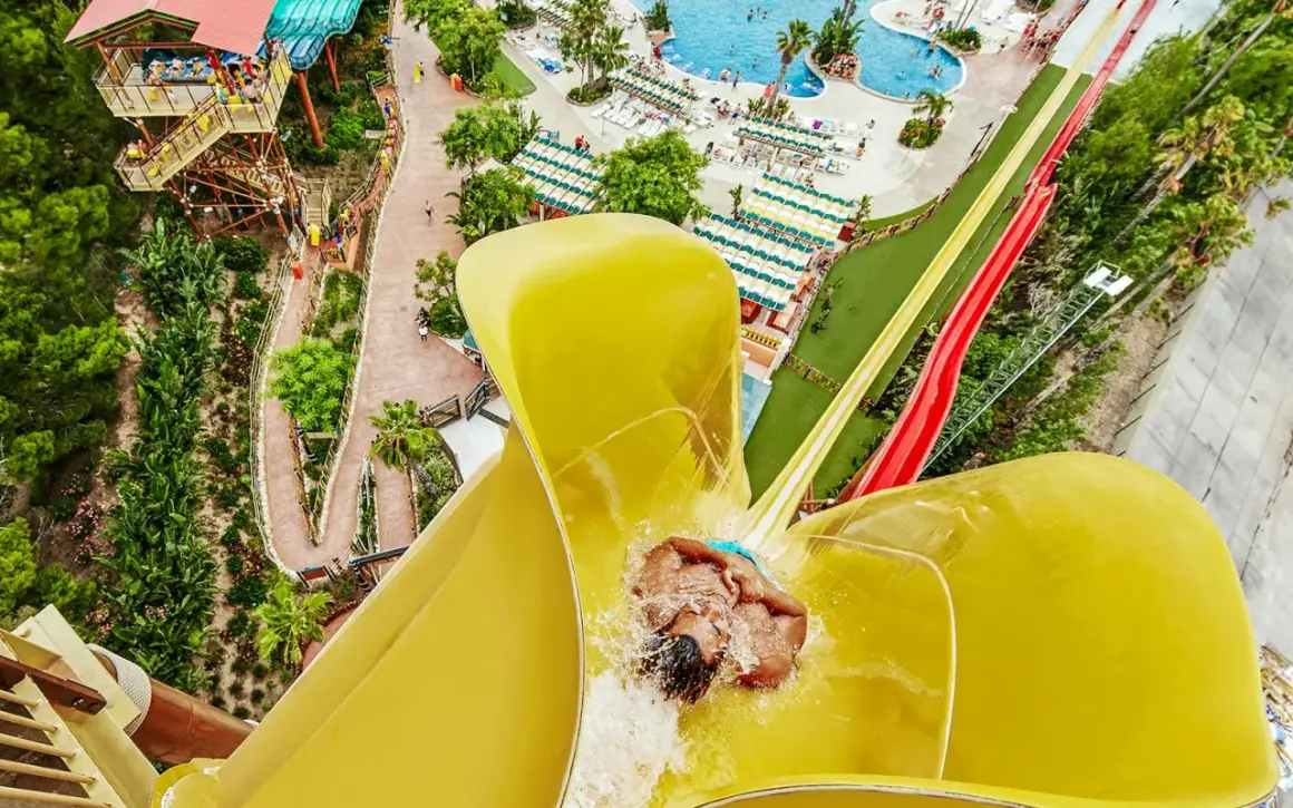 Persona deslizándose por un tobogán amarillo en PortAventura. ¡Descubre cómo llegar a este paraíso acuático!