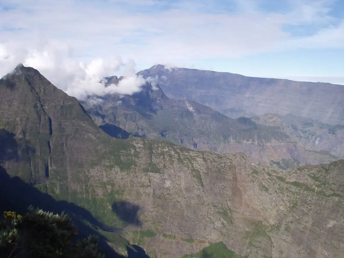 Impresionantes montañas en la isla Reunión, con nubes que envuelven picos escarpados, sugiriendo los peligros de su terreno.