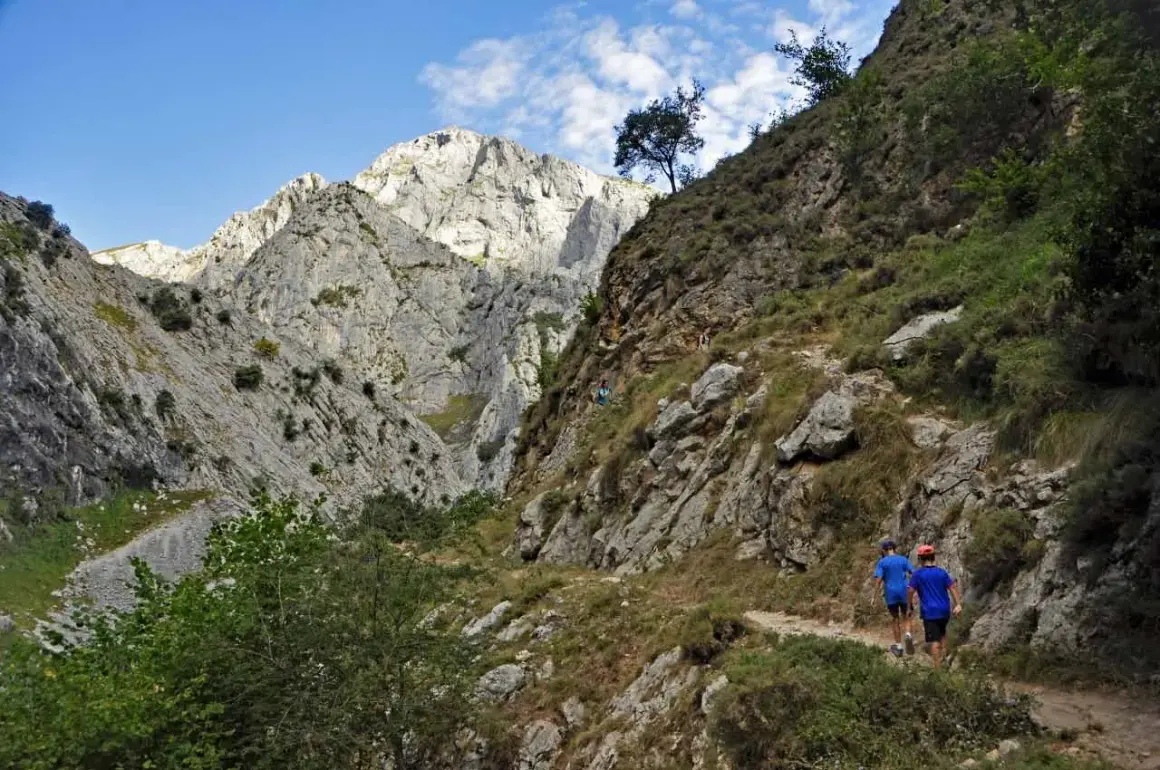 Dos niños caminan por un sendero rocoso en un desfiladero, una ruta para llegar a Bulnes.