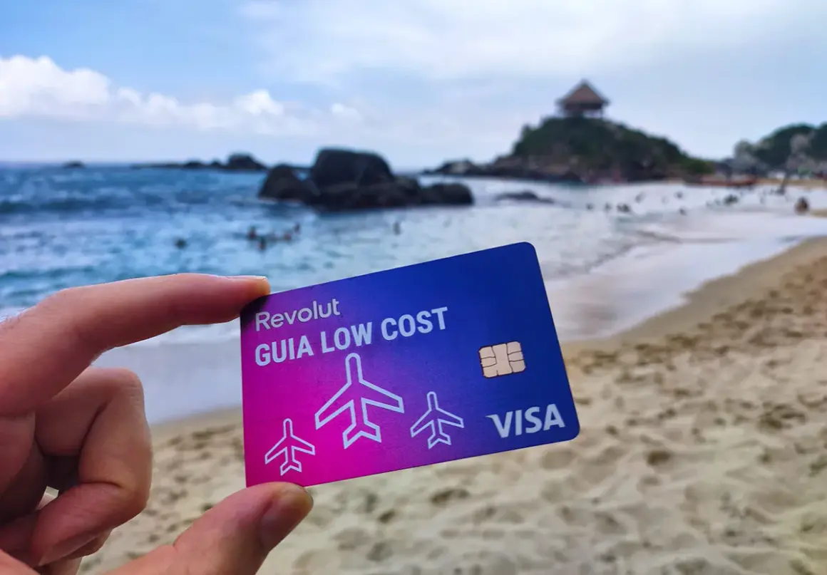 Tarjeta Revolut "Guía Low Cost" en una playa paradisíaca. Descubre cómo funciona Revolut en el extranjero sin comisiones ocultas.