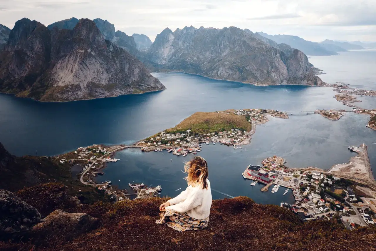 Mujer contempla las Islas Lofoten. Descubre c&oacute;mo llegar a este para&iacute;so noruego.