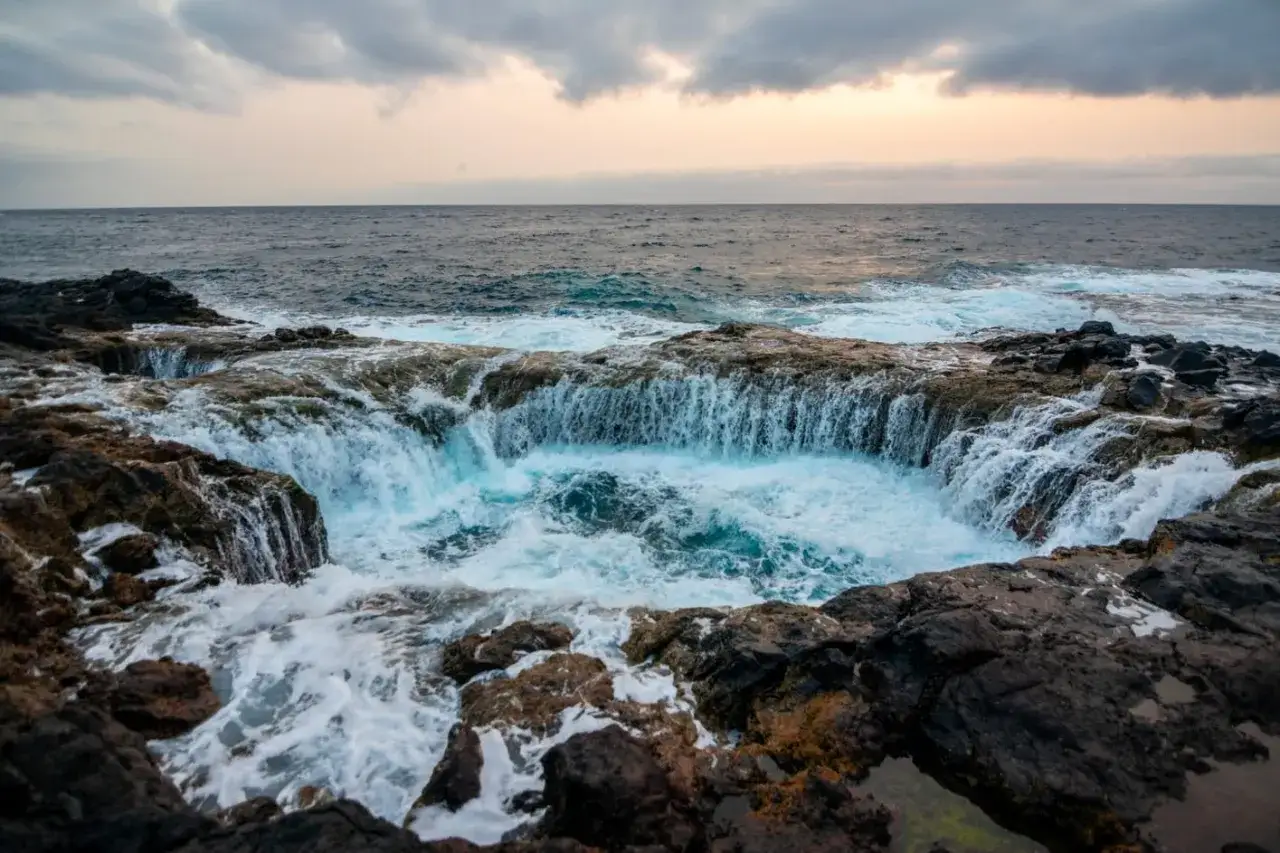 El mar choca contra las rocas volcánicas, creando una cascada natural en un agujero en la costa de Las Palmas de Gran Canaria.