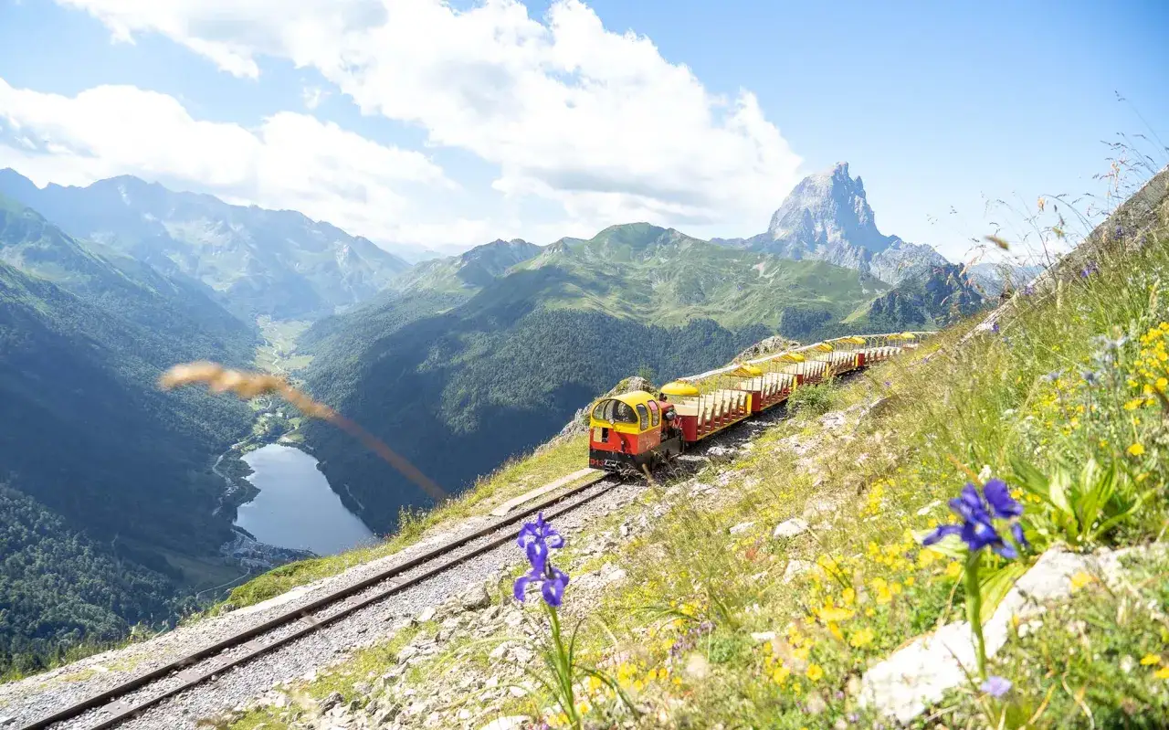 El tren de Artouste asciende por la montaña, ofreciendo vistas espectaculares del valle y el lago.