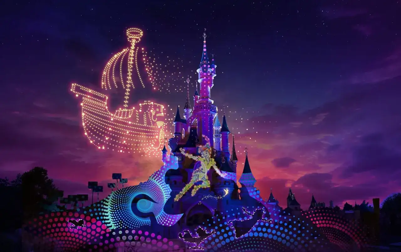 Castillo de Disneyland Paris iluminado con proyecciones de Peter Pan y un barco de luces, bajo un cielo estrellado y crepuscular.