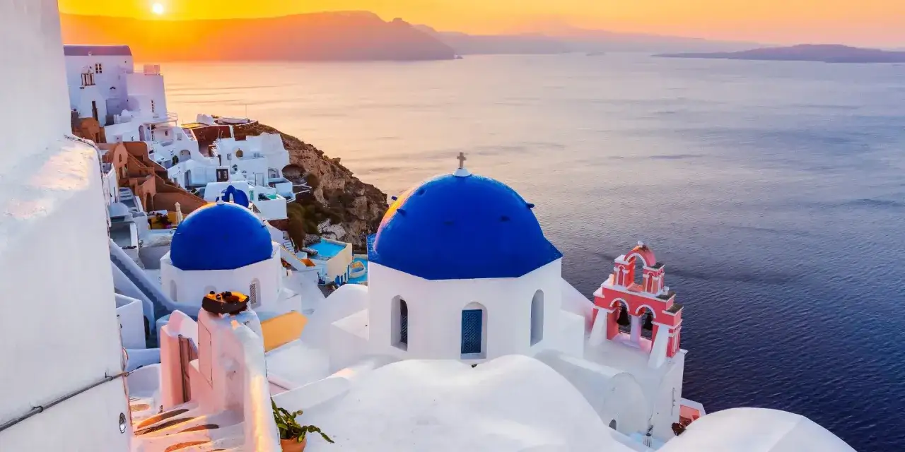 Iglesia de c&uacute;pula azul en Oia, Santorini, uno de los lugares de Grecia m&aacute;s ic&oacute;nicos, al atardecer.