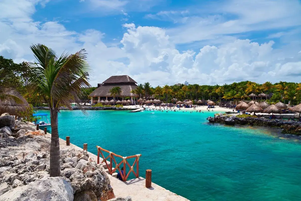 Playa caribeña con aguas turquesas, palmeras y un restaurante. Ideal para pensar donde viajar en marzo Europa, pero este paraíso es tentador.