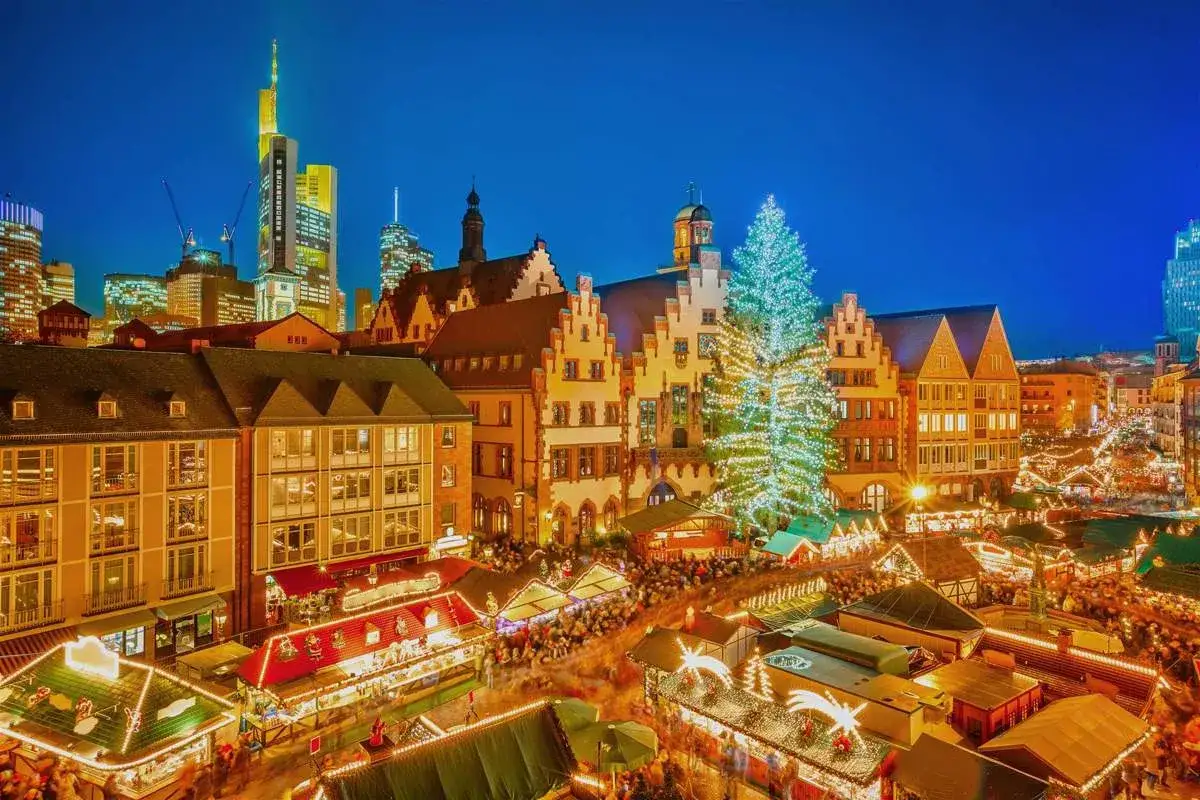 Mercados de Navidad en Alemania, con un árbol gigante iluminado y puestos festivos bajo un cielo nocturno.