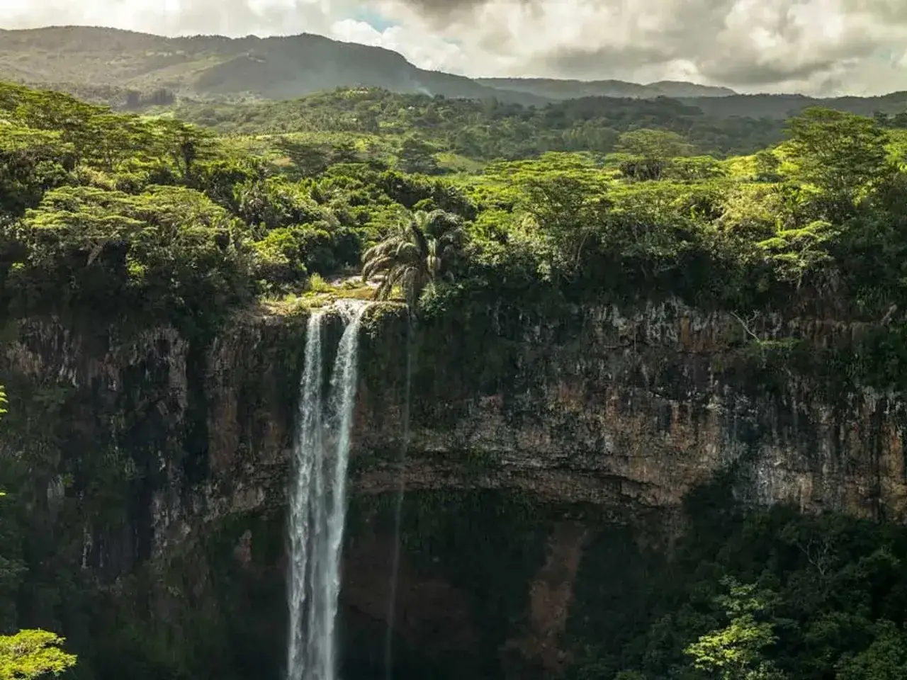 Cascada exuberante en Isla Mauricio, rodeada de vegetación tropical y montañas. Definitivamente merece la pena viajar a Isla Mauricio para ver esta maravilla natural.