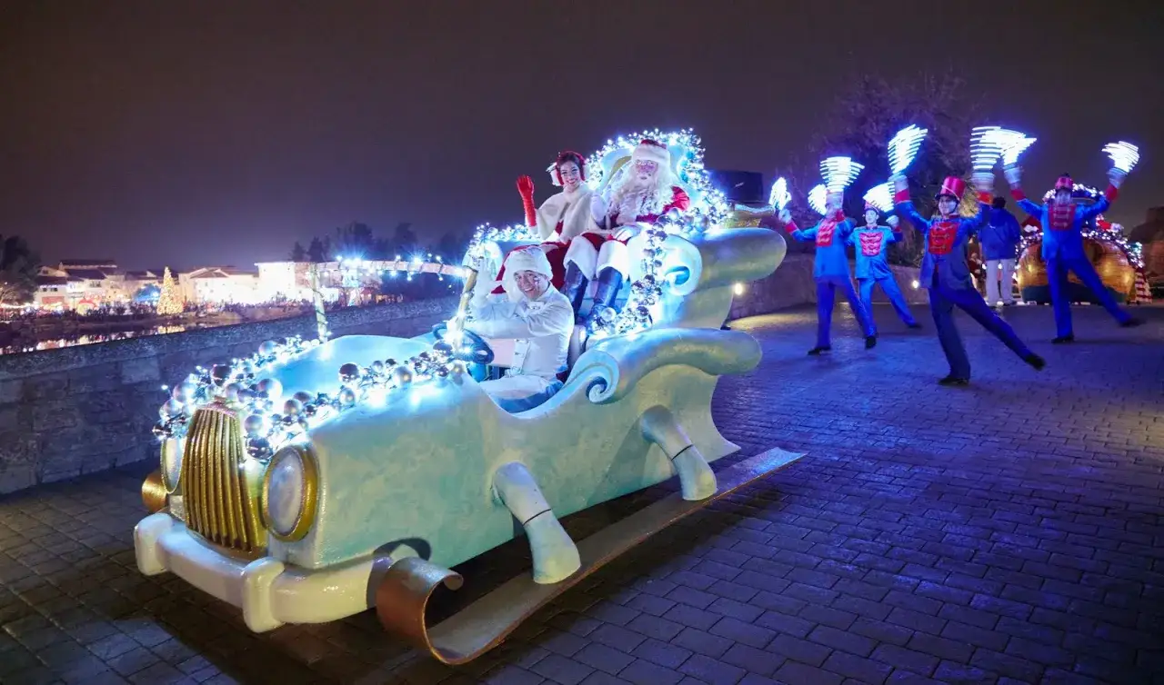 Pap&aacute; Noel y sus ayudantes desfilan en un trineo-coche iluminado en PortAventura en Navidad.