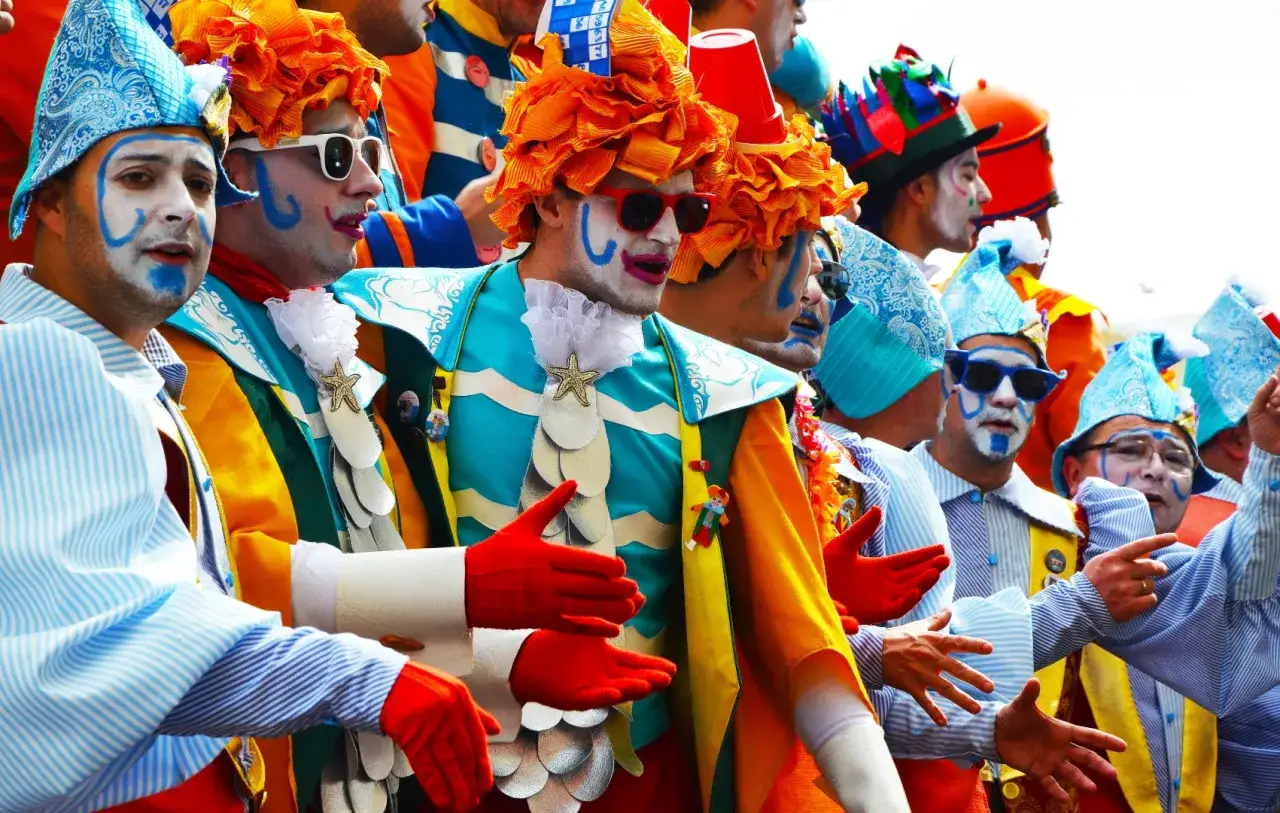 Gente disfrazada de payasos con maquillaje y trajes coloridos. ¡Un destino ideal donde viajar en febrero para celebrar el carnaval!
