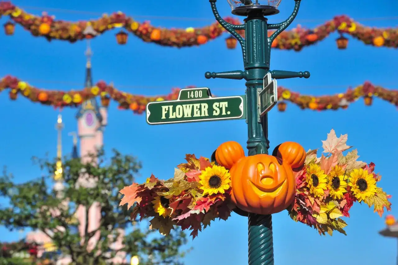 Decoración de Disneyland Paris Halloween con calabazas, girasoles y hojas de otoño adornan un poste de luz con el letrero