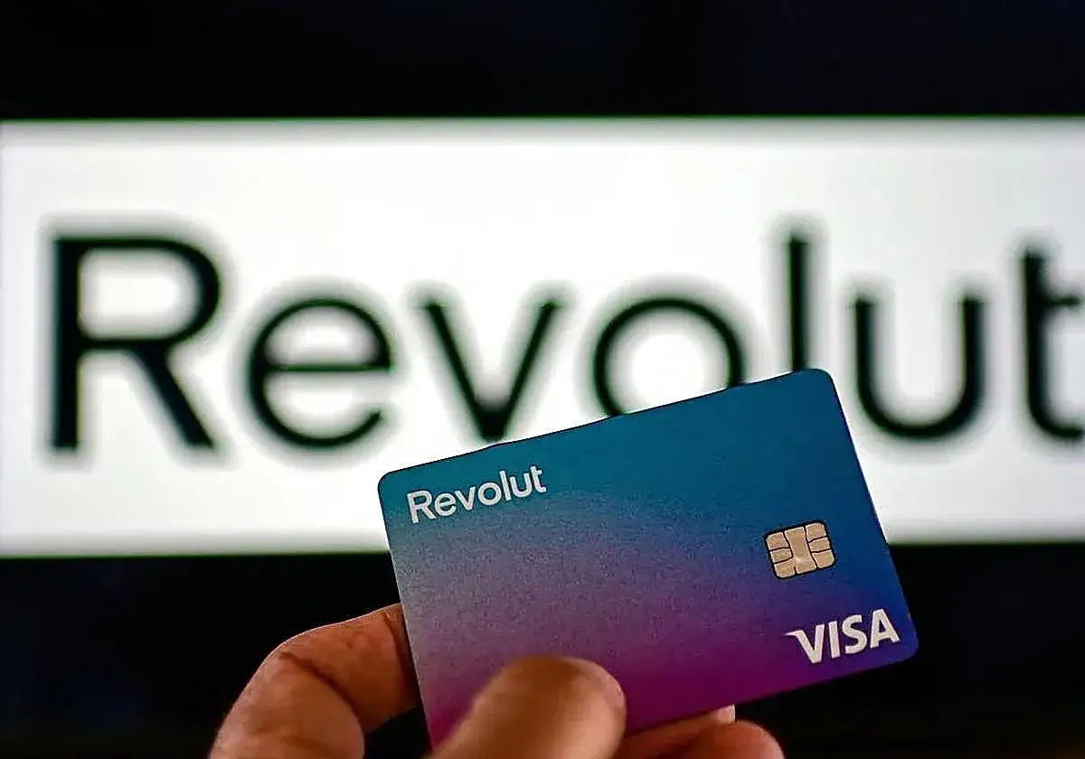 Tarjeta Revolut en mano, con el logo de la marca desenfocado al fondo. Descubre como funciona Revolut en el extranjero sin comisiones.