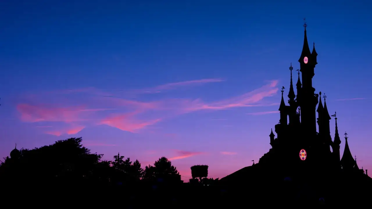 Silueta del castillo de Disneyland contra un cielo crepuscular azul y rosa.