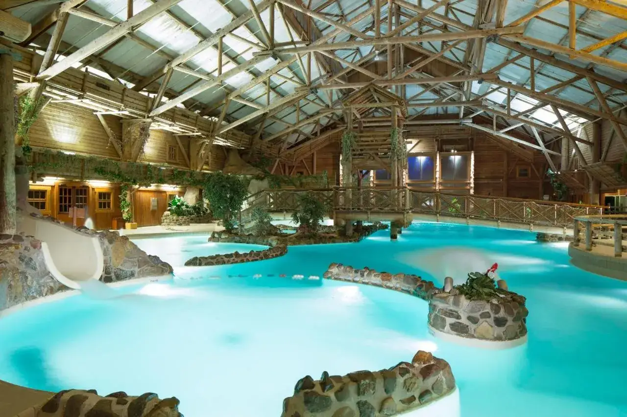 Piscina interior con tobogán y puentes de madera, ideal para un camping en Disneyland Paris.
