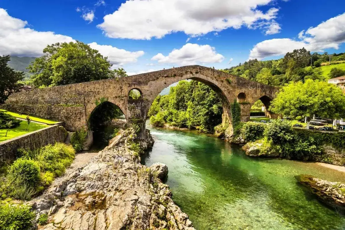 Puente medieval sobre r&iacute;o verde en Cangas de On&iacute;s. Un lugar id&iacute;lico para descubrir qu&eacute; ver en esta villa asturiana.