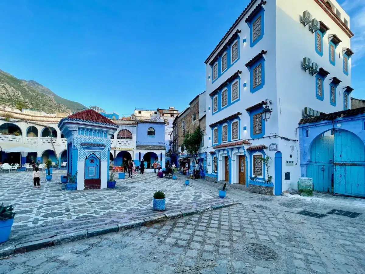 Plaza de Chefchaouen, con edificios blancos y azules, fuente central y gente paseando. A pesar de su belleza, Chefchaouen es peligroso.