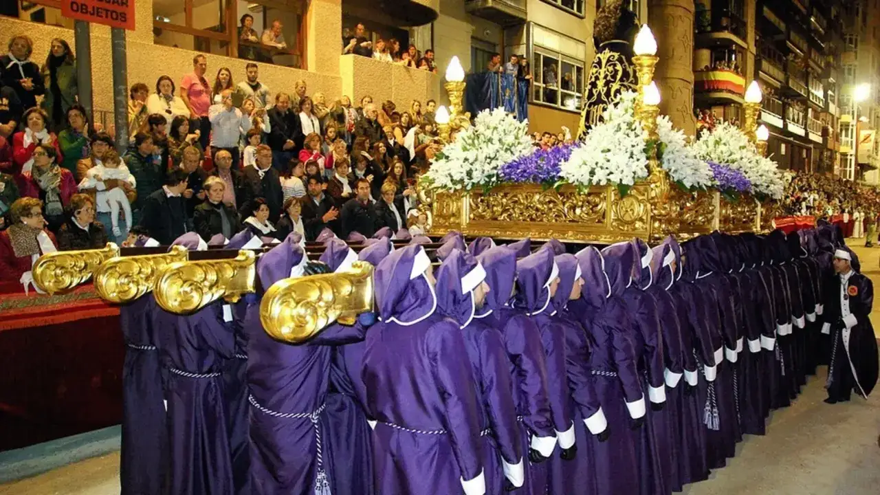 Procesión de Semana Santa con paso dorado y nazarenos morados. Un evento para considerar donde viajar en Semana Santa.
