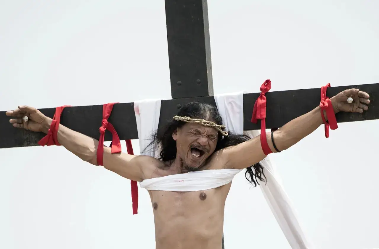 Un hombre con corona de espinas y atado a una cruz, con expresión de dolor, durante una representación de la Semana Santa Filipinas.