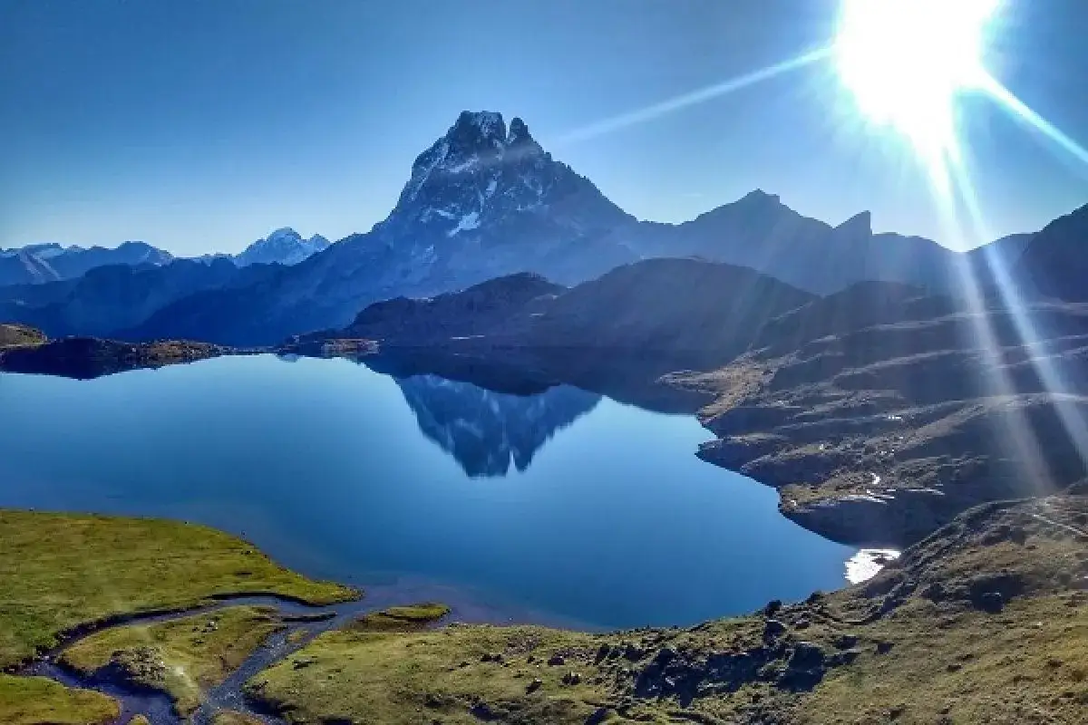 Reflejo perfecto de la monta&ntilde;a en los lagos de Ayous. El sol brilla intensamente sobre el paisaje alpino.