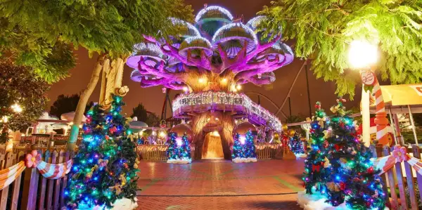Árboles de Navidad iluminados y decorados en PortAventura en Navidad, con un árbol central gigante y luces festivas.